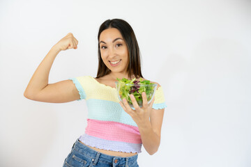 Portrait of a happy playful woman eating fresh salad from a bowl isolated over white background