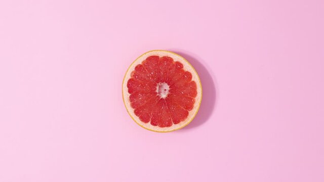 Citrus grapefruit rotating on  pastel pink background. Stop motion