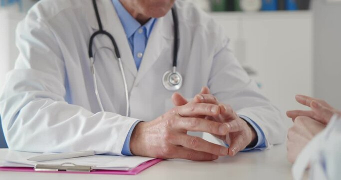 Close up of patient and doctor hands in medical office on table