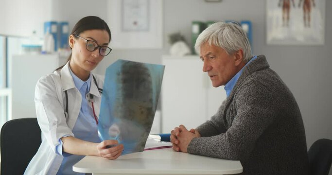 Female doctor studying an x-ray diagram with senior male patient