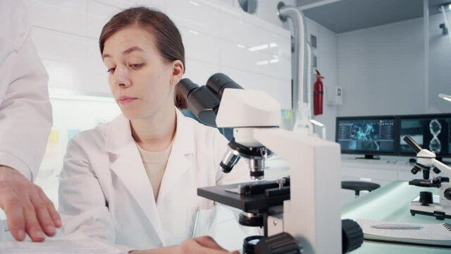 Microbiologist studying medical samples using microscopes. Virus models on computer screens