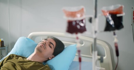 Young male patient getting blood transfusion in hospital ward - Powered by Adobe