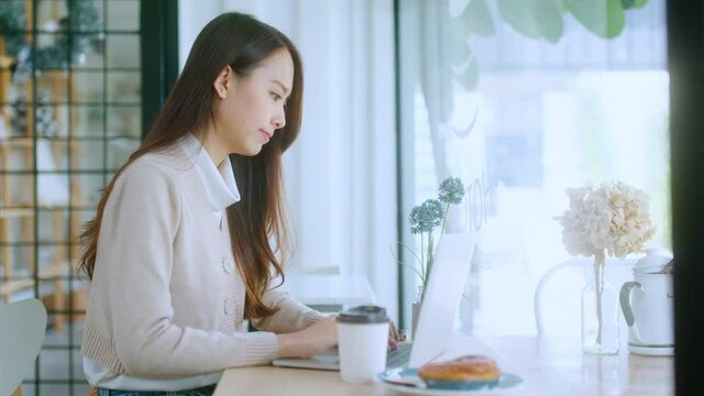 young attractive asian female wear casual cloth hand use smartphone and laptop device comminication social contact in cafe restaruant sit at counter next to big window daylight