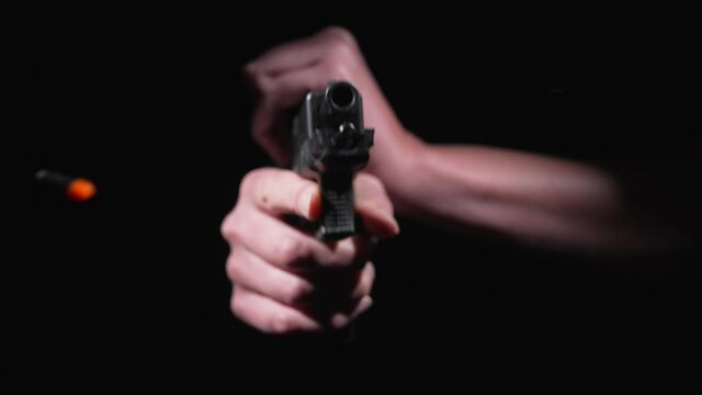 This slow motion video shows the front view of a gun being cocked and a shell bullet flying out.