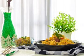 rice with chicken served on the table with yellow flowers