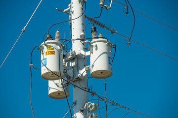 Electric pole and electric transformer on background clear blue sky. Electrical power lines. High...