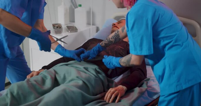 Doctor and nurse cutting shirt of male patient preparing for reanimation