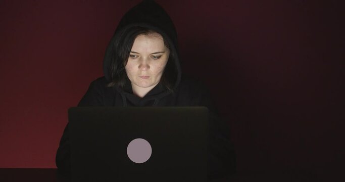 Programmer working on laptop against dark background