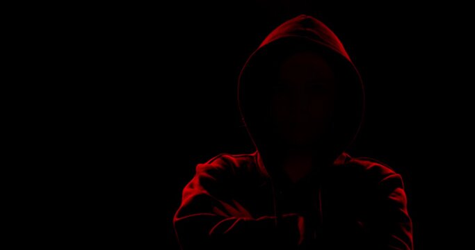Silhouette of man in hoodie on dark background