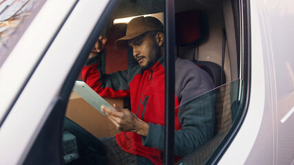 Happy indian courier using tablet in the van . High quality photo