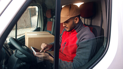 Happy indian courier using tablet in the van . High quality photo - Powered by Adobe