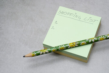 A handwritten shopping list on A Post-it Sticky Notes..Green square shape memo pad..Grey background..Organization concept. .Shopping planning concept. - 429719632