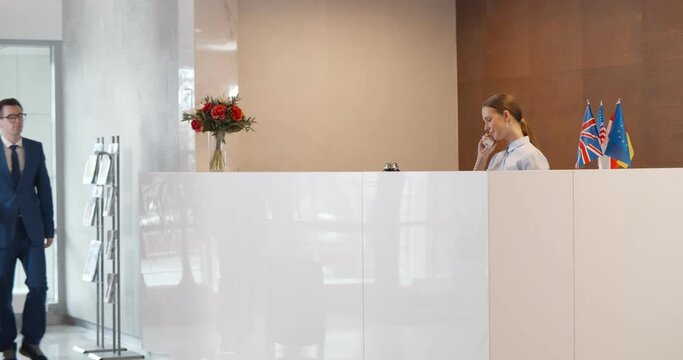 Businessman making booking at front desk with female receptionist in hotel lobby