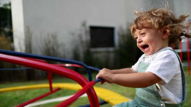 Fun loving baby shaking head while spinning at playground caroussel