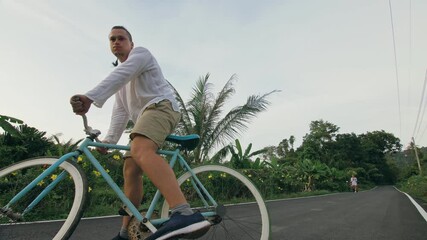Biking road trip. The man on blue bike in white clothes on forest road. The biker men ride on bicycle. Cycling Cycle Fix. Asia Thailand ride tourism.