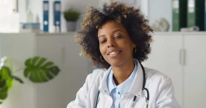 Young smiling afro-american woman doctor sitting in clinic office.