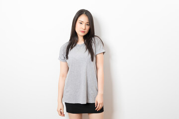 Portrait of beautiful young asian woman wearing grey shirt over white background.