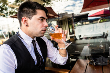 Young Latino entrepreneur sitting in a bar and drinking a glass of beer.