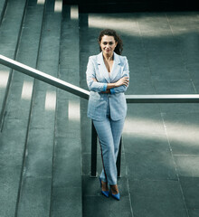 Business, people and lifestyle concept: young african woman in a stylish blue suit stands near the stairs.