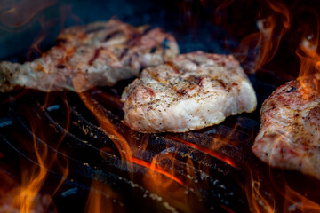 Pork steaks on the grill with flames
