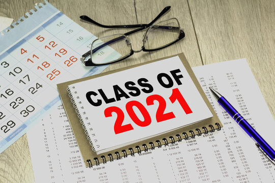 CLASS OF 2021. blank notebook with markers pen beside. The notebook is on paper with text . Colored pencils and eyeglasses. Concept photo.