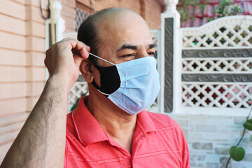 double mask prevent infection, mature indian man wearing two face mask to protect from new strain...
