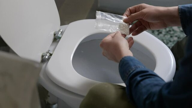 Cropped View Of Man Pouring Out Cocaine In Toilet Bowl In Modern Restroom - close up shot