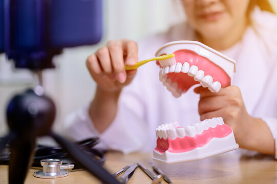 Asian dentist woman working online at home. Recording blog video for tutorial instructional brushing teeth clean. Dentistry and teeth health care.