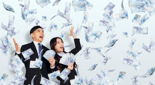 Excited young business man and woman holding  with dollars under money rain