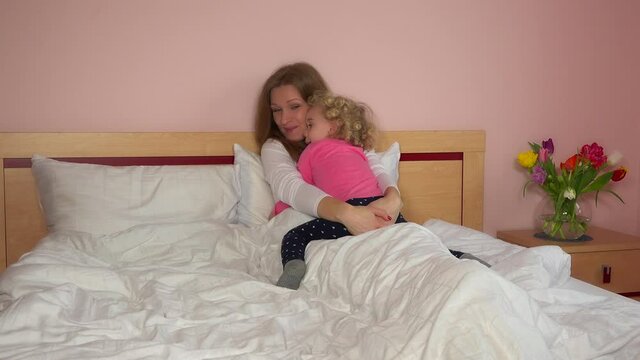mother sit hugging in bed with her daughter. Love, family and free time 4K