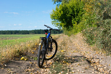 Fototapeta na wymiar Mountain bike. bike stands on in the field. A mountain bike stands on a field path with green grass. cycling. outdoor cycling activities. space for text. editorial, Ukraine, Kiev region 2020