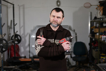 Fototapeta na wymiar Portrait of adult caucasian man with beard with screwdriver in hands in garage