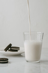 Milk pouring into a glass to accompany some chocolate cookies. Something that everyone likes
