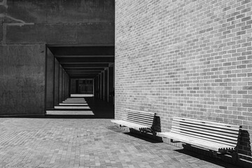 A black and white version of a brick wall and benches with shadows