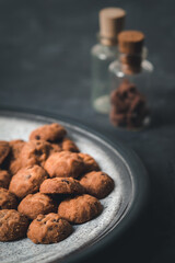 Plate of small cookies with chocolate chips on a high contrast gray surface.