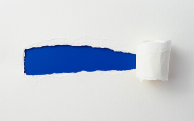 torn paper with the curled ripped sides. a long blue hole of torn on the white paper. realistic torn paper with the ripped edges for copy space and text.