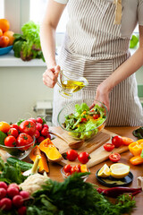 Beautiful young woman preparing delicious fresh vitamin salad with olive oil. Concept of clean eating, healthy food, low calories meal, dieting, self caring lifestyle. Colorful vegetables. Close up