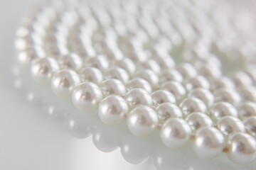 A necklace of pearls lying on white glass
