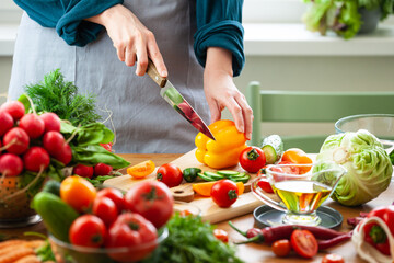 Beautiful young woman slicing yellow pepper, preparing delicious fresh vitamin salad. Concept of clean eating, healthy food, low calories meal, dieting, self caring lifestyle. Close up