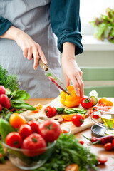 Beautiful young woman slicing yellow pepper, preparing delicious fresh vitamin salad. Concept of...