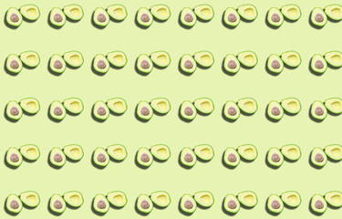 Fototapeta na wymiar A pattern of two avocado halves with a shadow on a green background.