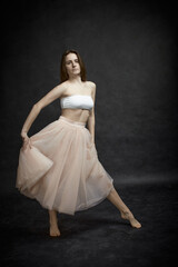 Fototapeta premium Young girl in white top and peach skirt dancing