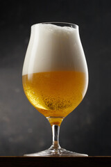 Glass with light golden beer on a dark background