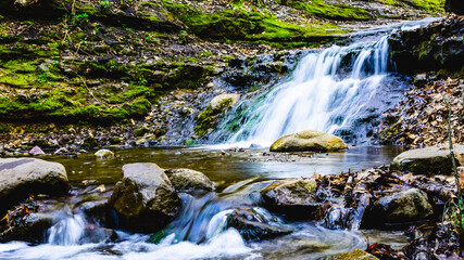 Obraz premium Waterfall in the forest with green mossy rock.