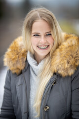 Portraits of a young blonde woman with braces laughs beaming and looks to the left..