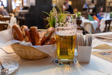 Classic German dinner of fried sausages with braised cabbage on large white plates with light beer, standing on table in restaurant interior.