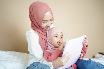 Muslim mother teaching her daughter to read the book.