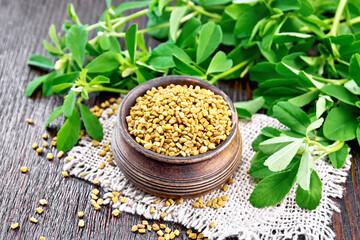 Fenugreek in bowl with leaves on dark wooden board