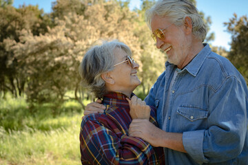 Portrait of beautiful senior couple enjoying outdoor excursion in the countryside looking into each other's eyes. Two mature people and nature