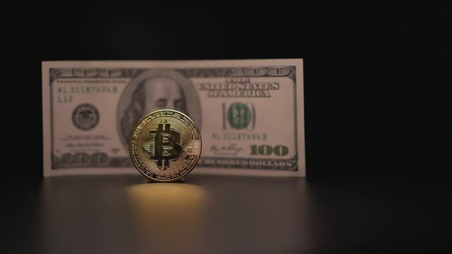 A senseless and thoughtless waste of money in the form of investments in cryptocurrency. Bitcoin icon on the background of a hundred dollar bill. American banknote with gold bitcoin.